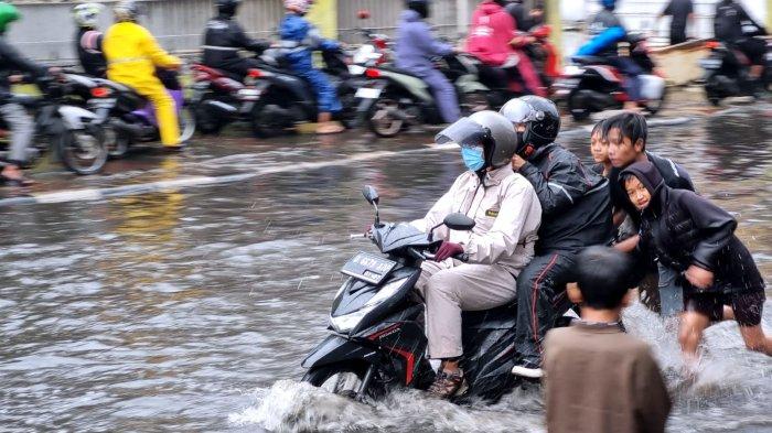 Sejumlah warga mendorong sepeda motor yang mogok saat menerjang banjir cileuncang yang merendam Jalan Kopo Citarip, Kelurahan Kopo, Kecamatan Bojongloa Kaler, Kota Bandung, Jawa Barat, Selasa (24/10/2023).