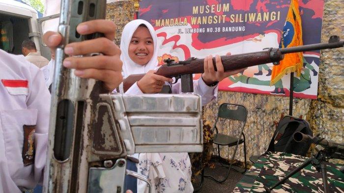 Pelajar mencoba memegang senjata laras panjang yang digunakan pada masa penjajahan koleksi Museum Mandala Wangsit dalam gelaran Museum Monpera Expo di pelataran Moseum Perjuangan Rakyat Jawa Barat (Monpera Jabar), Jalan Dipatiukur, Kota Bandung, Jawa Barat, Kamis (2/11/2023).