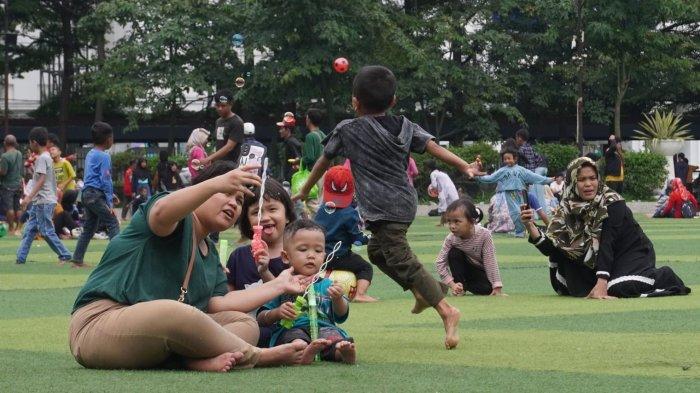 Warga mengisi liburan di lapangan rumput sintetis Taman Alun-alun Kota Bandung, Jawa Barat, Selasa (2/1/2024).