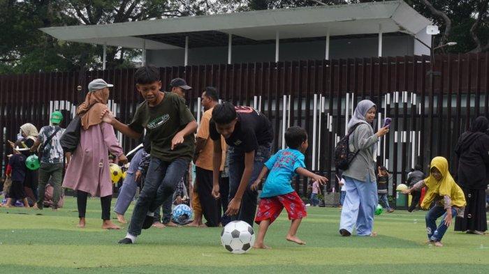 Warga mengisi liburan di lapangan rumput sintetis Taman Alun-alun Kota Bandung, Jawa Barat, Selasa (2/1/2024).