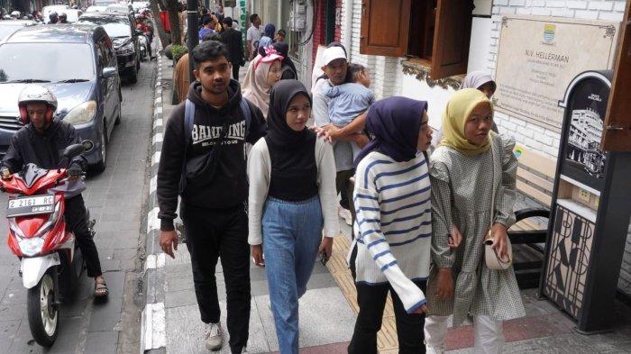 Wisatawan menyusuri trotoar yang lebar sambil melintasi bangunan tempo dulu di sepanjang Jalan Braga, Kota Bandung, Jawa Barat, Sabtu (6/1/2024).