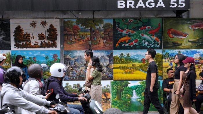 Wisatawan melewati sejumlah lukisan yang dijual dan dipajang di salah satu titik di Jalan Braga, Kota Bandung, Jawa Barat, Sabtu (6/1/2024).