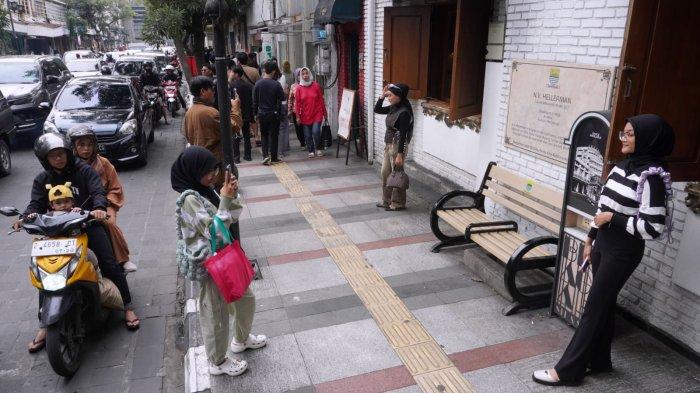 Wisatawan berfoto dengan latar bangunan tempo dulu di Jalan Braga, Kota Bandung, Jawa Barat, Sabtu (6/1/2024).
