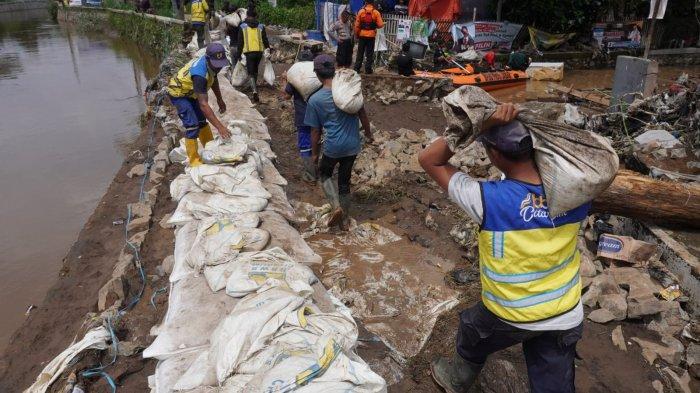 Petugas membuat tanggul sementara dengan karung berisi pasir di tanggul Sungai Cigede yang jebol, di Kampung Lamajang Peuntas, Desa Citeureup, Kecamatan Dayeuhkolot, Kabupaten Bandung, Jawa Barat, Jumat (12/1/2024).