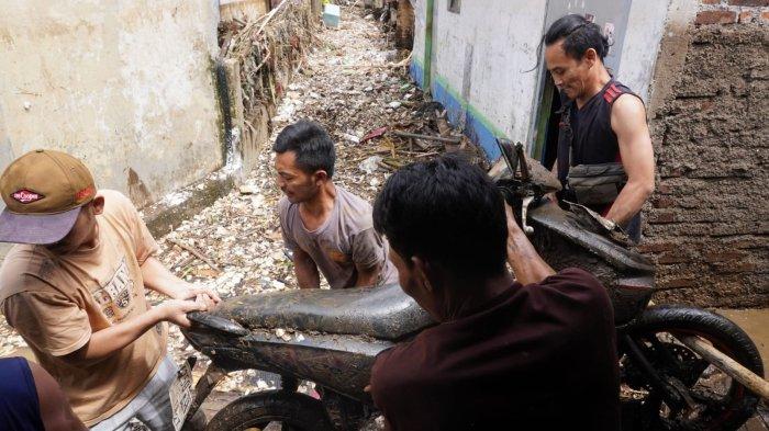 Warga mengevakuasi satu unit sepeda motor yang tertimbun lumpur dan material sampah di sekitar lokasi tanggul Sungai Cigede yang jebol, di Kampung Lamajang Peuntas, Desa Citeureup, Kecamatan Dayeuhkolot, Kabupaten Bandung, Jawa Barat, Jumat (12/1/2024).