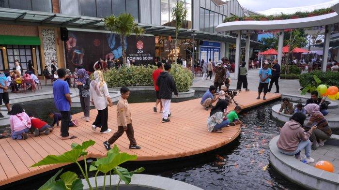 Warga bermain dengan ikan koi yang ada di kolam, di area luar Summarecon Mall Bandung (Summaba) seusai resmi dibuka, di kawasan Summarecon Bandung, Gedebage, Kota Bandung, Jawa Barat, Kamis (18/1/2024).