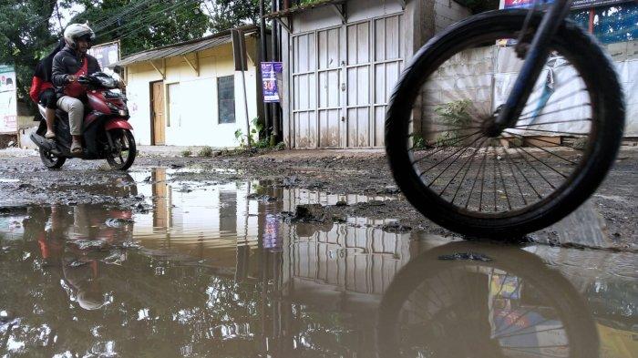 Pengguna jalan melintasi jalan rusak berkubang air di Jalan Radio Palasari, Desa Citeureup, Kecamatan Dayeuhkolot, Kabupaten Bandung, Jawa Barat, Selasa (23/1/2024).