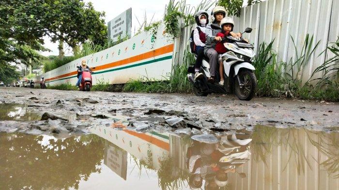 Pengguna jalan melintasi jalan rusak berkubang air di Jalan Radio Palasari, Desa Citeureup, Kecamatan Dayeuhkolot, Kabupaten Bandung, Jawa Barat, Selasa (23/1/2024).