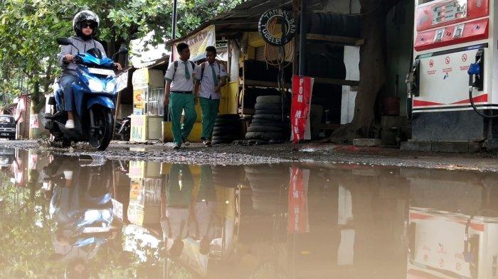 Pengguna jalan melintasi jalan rusak berkubang air di Jalan Radio Palasari, Desa Citeureup, Kecamatan Dayeuhkolot, Kabupaten Bandung, Jawa Barat, Selasa (23/1/2024).