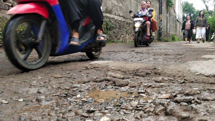 Pengguna jalan melintasi jalan rusak di Kampung Cilebak, Desa Rancamanyar, Kecamatan Baleendah, Kabupaten Bandung, Jawa Barat, Selasa (6/2/2024).