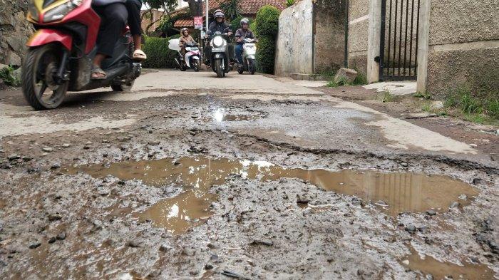 Pengguna jalan melintasi jalan rusak di Kampung Cilebak, Desa Rancamanyar, Kecamatan Baleendah, Kabupaten Bandung, Jawa Barat, Selasa (6/2/2024).