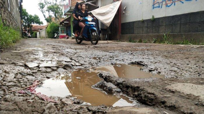Pengguna jalan melintasi jalan rusak di Kampung Cilebak, Desa Rancamanyar, Kecamatan Baleendah, Kabupaten Bandung, Jawa Barat, Selasa (6/2/2024).