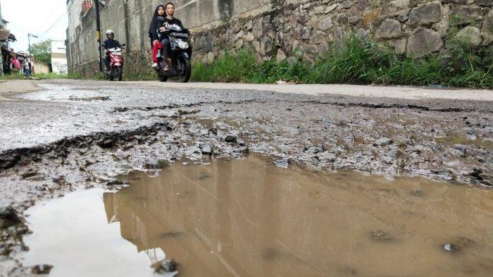 Pengguna jalan melintasi jalan rusak di Kampung Cilebak, Desa Rancamanyar, Kecamatan Baleendah, Kabupaten Bandung, Jawa Barat, Selasa (6/2/2024).
