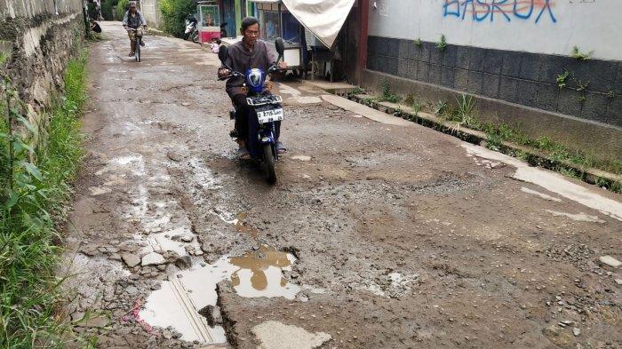 Pengguna jalan melintasi jalan rusak di Kampung Cilebak, Desa Rancamanyar, Kecamatan Baleendah, Kabupaten Bandung, Jawa Barat, Selasa (6/2/2024).