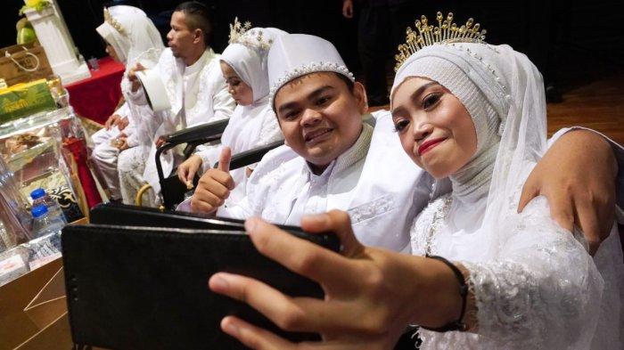 Sepasang pengantin difabel berswafoto saat mengikuti nikah massal di Teater Tertutup Dago Tea House Taman Budaya Jawa Barat, Jalan Bukit Utara, Kota Bandung, Jawa Barat, Rabu (28/2/2024).