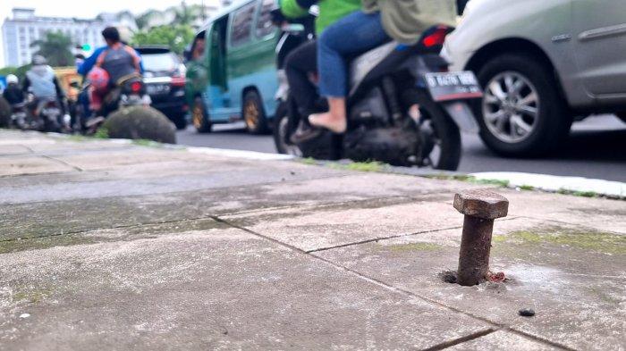 Kendaraan bermotor melintasi batu bulat yang lepas dan berada di pinggir badan jalan di Jalan Tamblong, Kota Bandung, Jawa Barat, Kamis (25/4/2024).