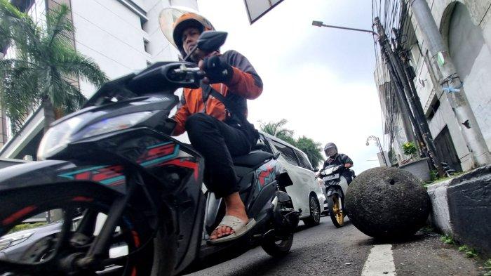 Kendaraan bermotor melintasi batu bulat yang lepas dan berada di pinggir badan jalan di Jalan Tamblong, Kota Bandung, Jawa Barat, Kamis (25/4/2024).