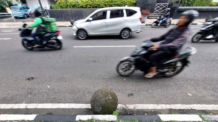 Kendaraan bermotor melintasi batu bulat yang lepas dan berada di pinggir badan jalan di Jalan Tamblong, Kota Bandung, Jawa Barat, Kamis (25/4/2024).