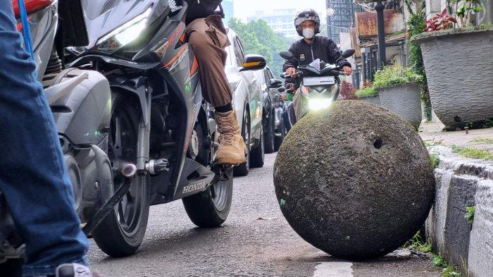 Kendaraan bermotor melintasi batu bulat yang lepas dan berada di pinggir badan jalan di Jalan Tamblong, Kota Bandung, Jawa Barat, Kamis (25/4/2024).