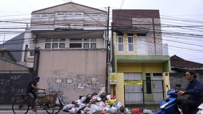 Pengguna jalan melintasi sampah yang sudah menumpuk di depan salah satu rumah di pinggir Jalan Sayuran, Desa Cangkuang Kulon, Kecamatan Dayeuhkolot, Kabupaten Bandung, Jawa Barat, Jumat (26/4/2024).