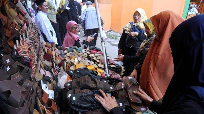 Wisatawan berbelanja sandal di sekitar kompleks pemakaman seusai berziarah di makam Mama Eyang Cibaduyut, KH RD Muhammad Zarkasyi, di Jalan Cibaduyut Raya, Gang Pesantren, Kelurahan Cibaduyut, Kecamatan Bojongloa Kidul, Kota Bandung, Jawa Barat, Sabtu (27/4/2024).