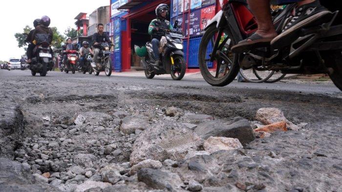 Kendaraan bermotor melintasi permukaan jalan yang rusak di Jalan Patrol, Desa Sukamukti, Kecamatan Katapang, Kabupaten Bandung, Jawa Barat, Senin (29/4/2024).