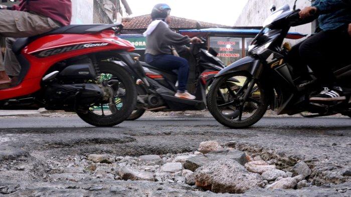 Kendaraan bermotor melintasi permukaan jalan yang rusak di Jalan Patrol, Desa Sukamukti, Kecamatan Katapang, Kabupaten Bandung, Jawa Barat, Senin (29/4/2024).