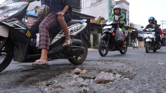Kendaraan bermotor melintasi permukaan jalan yang rusak di Jalan Patrol, Desa Sukamukti, Kecamatan Katapang, Kabupaten Bandung, Jawa Barat, Senin (29/4/2024).