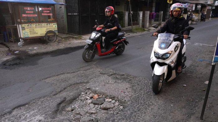 Kendaraan bermotor melintasi permukaan jalan yang rusak di Jalan Patrol, Desa Sukamukti, Kecamatan Katapang, Kabupaten Bandung, Jawa Barat, Senin (29/4/2024).