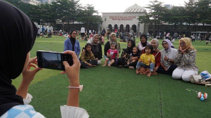 Pengunjung berfoto bersama di lapangan rumput sintetis Taman Alun-Alun Kota Bandung, Jawa Barat, Kamis (9/5/2024).