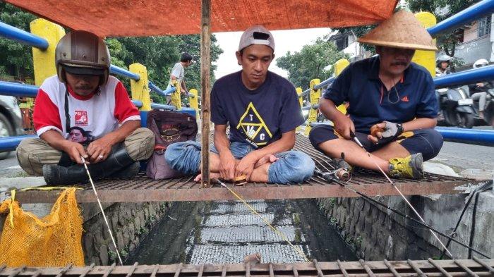 Warga memancing ikan lele di selokan yang membelah Jalan Leuwipanjang, Kota Bandung, Jawa Barat, Kamis (9/5/2024).