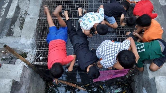 Warga memancing ikan lele di selokan yang membelah Jalan Leuwipanjang, Kota Bandung, Jawa Barat, Kamis (9/5/2024).