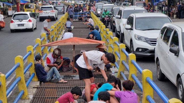 Warga memancing ikan lele di selokan yang membelah Jalan Leuwipanjang, Kota Bandung, Jawa Barat, Kamis (9/5/2024).
