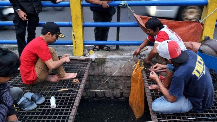 Warga memancing ikan lele di selokan yang membelah Jalan Leuwipanjang, Kota Bandung, Jawa Barat, Kamis (9/5/2024).