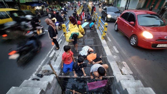 Warga memancing ikan lele di selokan yang membelah Jalan Leuwipanjang, Kota Bandung, Jawa Barat, Kamis (9/5/2024).