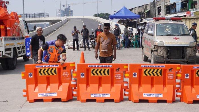 Petugas Dishub Kota Bandung memasang water barrier atau pembatas jalan menggantikan kayu, meja dan spanduk yang sebelumnya dipasang oleh warga menutup akses jalan ke Flyover Ciroyom di Kelurahan Ciroyom, Kecamatan Andir, Kota Bandung, Jawa Barat, Senin (20/5/2024).
