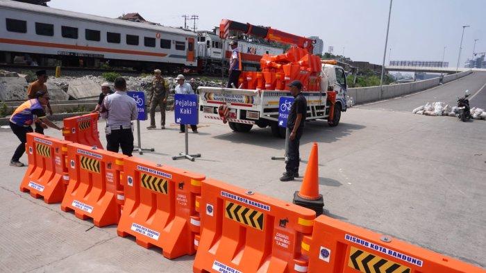 Petugas Dishub Kota Bandung memasang water barrier atau pembatas jalan menggantikan kayu, meja dan spanduk yang sebelumnya dipasang oleh warga menutup akses jalan ke Flyover Ciroyom di Kelurahan Ciroyom, Kecamatan Andir, Kota Bandung, Jawa Barat, Senin (20/5/2024).