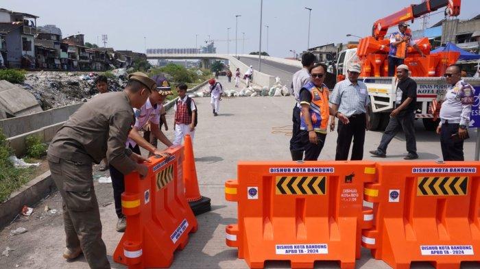 Petugas Dishub Kota Bandung memasang water barrier atau pembatas jalan menggantikan kayu, meja dan spanduk yang sebelumnya dipasang oleh warga menutup akses jalan ke Flyover Ciroyom di Kelurahan Ciroyom, Kecamatan Andir, Kota Bandung, Jawa Barat, Senin (20/5/2024).