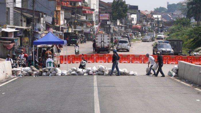 Warga memasang kembali karung berisi pasir setelah Petugas Dishub Kota Bandung memasang water barrier atau pembatas jalan menggantikan kayu, meja dan spanduk yang sebelumnya dipasang oleh warga menutup akses jalan ke Flyover Ciroyom di Kelurahan Ciroyom, Kecamatan Andir, Kota Bandung, Jawa Barat, Senin (20/5/2024).