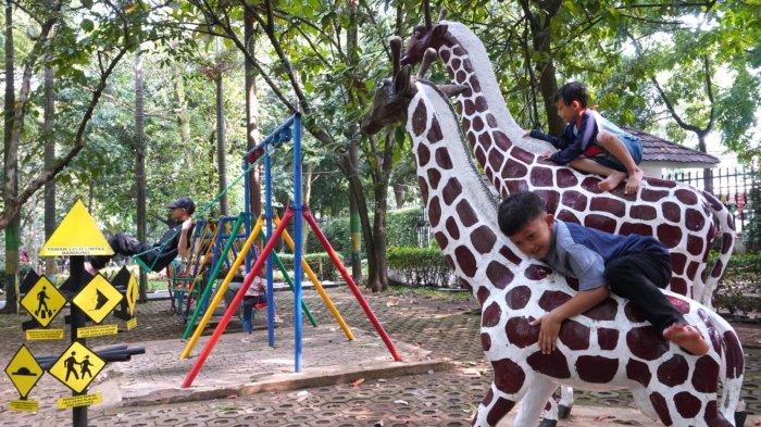 Pengunjung bermain ayunan dan naik patung jerapah saat berwisata di Taman Lalu Lintas Ade Irma Suryani Nasution, Kota Bandung, Jawa Barat, Kamis (23/5/2024).