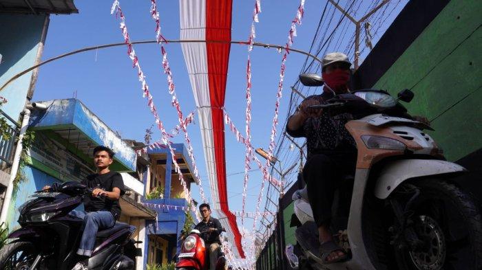 Pengendara sepeda motor melintas di Jalan Kampung Mengger Hilir yang dihiasi bendera dan rarawisan merah putih, di RW 03, Kampung Mengger Hilir, Desa Sukapura, Kecamatan Dayeuhkolot Kabupaten Bandung, Sabtu (10/8/2024).