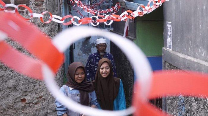 Warga melintas di salah satu gang yang dihiasi slinger merah putih, di RW 03, Kampung Mengger Hilir, Desa Sukapura, Kecamatan Dayeuhkolot Kabupaten Bandung, Sabtu (10/8/2024).