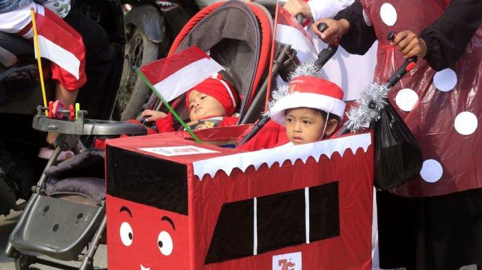 Dua balita dengan pernak-pernik merah putih mengikuti karnaval kemerdekaan, di Kampung Cilebak, RT 05 RW 02, Desa Rancamanyar, Kecamatan Baleendah, Kabupaten Bandung, Jawa Barat, Sabtu (17/8/2024).