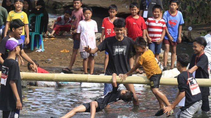 Anak-anak mengikuti lomba pukul bantal di Sungai Cidurian yang dibendung di saat airnya surut, di RW 15, Kelurahan Padasuka, Kecamatan Cibeunying Kidul, Kota Bandung, Jawa Barat, Sabtu (17/8/2024).
