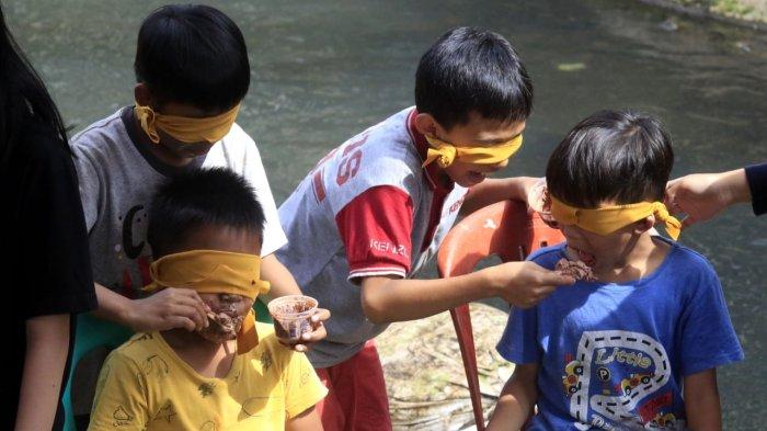 Anak-anak mengikuti lomba makan es krim dengan mata tertutup di Sungai Cidurian yang diuruk tanah di saat airnya surut, di RW 15, Kelurahan Padasuka, Kecamatan Cibeunying Kidul, Kota Bandung, Jawa Barat, Sabtu (17/8/2024).