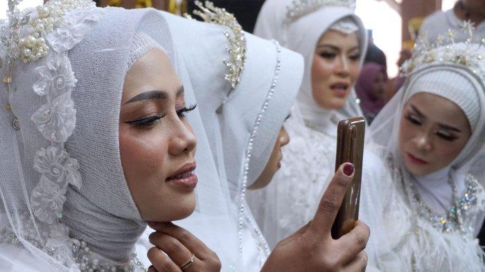 Seorang pengatin perempuan berkaca ke posel sambil merapikan bagian kerudungnya pada kegiatan nikah massal di Pendopo Kota Bandung, Jalan Dalem Kaum, Kota Bandung, Jawa Barat, Sabtu (21/9/2024).