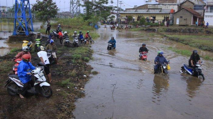 Pengendara sepeda motor nekat melintasi banjir cukup dalam di Jalan Saketi dan Jalan Pandeureusan, perbatasan Desa Rancamanyar dan Desa Cangkuang Wetan, di Kabupaten Bandung, Rabu (11/9/2024).