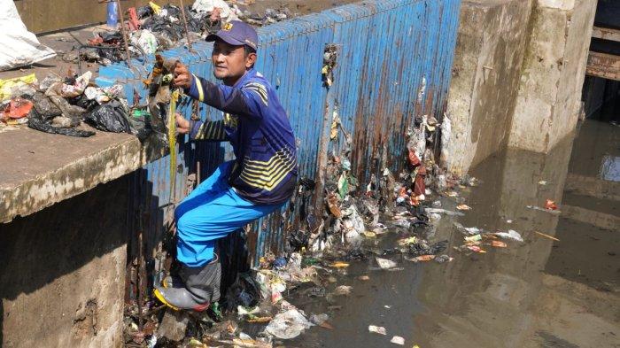 Petugas Polder Cipalasari 1, Nana Suntana (40) membersihkan sampah yang nyangkut dan menyumbat di besi penyaringan kolam penampungan air pengendali banjir Polder Cipalasari 1, Kampung Citeureup, Desa/Kecamatan Dayeuhkolot, Kabupaten Bandung, Jawa Barat, Kamis (12/9/2024).