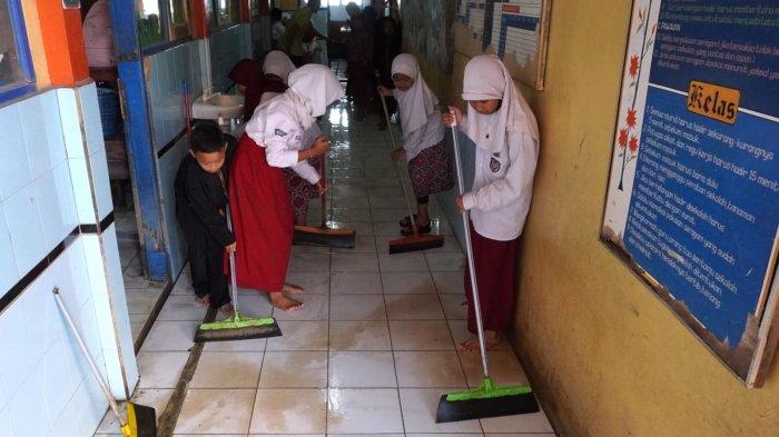Sejumlah siswa membuang sisa air di teras pasca banjir di SDN Bojongasih 02, Jalan Tubagus Anom, Kampung Bojongasih, Desa/Kecamatan Dayeuhkolot, Kabupaten Bandung, Jawa Barat, Kamis (12/9/2024).
