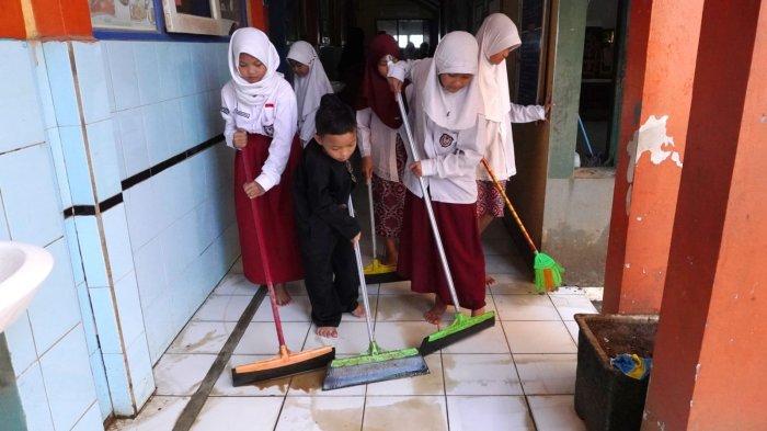 Sejumlah siswa membuang sisa air di teras pasca banjir di SDN Bojongasih 02, Jalan Tubagus Anom, Kampung Bojongasih, Desa/Kecamatan Dayeuhkolot, Kabupaten Bandung, Jawa Barat, Kamis (12/9/2024).